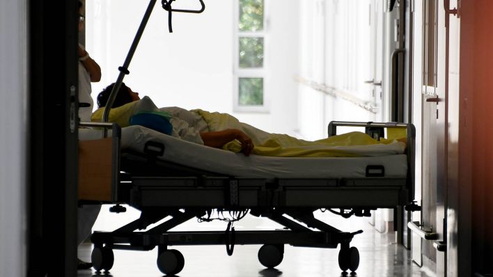 Ein Bett mit einem Patient steht in der Havelland-Klinik-Nauen auf dem Flur vor einem Fahrstuhl. (Quelle: dpa/Bernd Settnik)