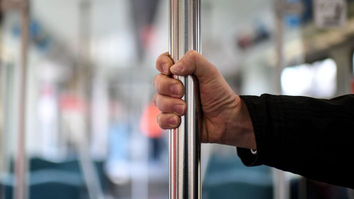 Ein Mann hält sich an einer Haltestange in der S-Bahn fest. (Quelle: dpa/Britta Pedersen)