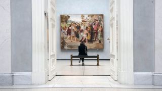 Eine Frau sitzt in der Alten Nationalgalerie vor dem Bild von Friedrich Overbeck. (Quelle: dpa/Paul Zinken)
