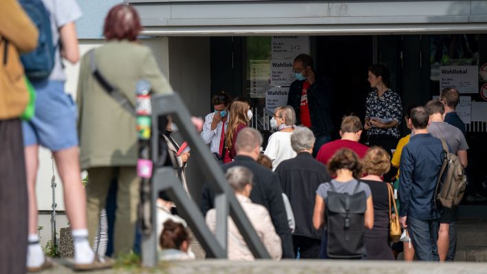 Zahlreiche Menschen stehen in einer langen Schlange vor den Wahllokalen im Tiergarten Gymnasium in der Altonaer Straße. (Quelle: dpa/Monika Skolimowska)