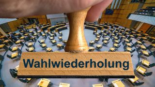 Ein symbolischer Holzstempel mit der Aufschrift "Wahlwiederholung", gehalten von einer Hand über dem Plenarsaal im Abgeordnetenhaus in Berlin. (Foto: picture alliance/sulupress.de)