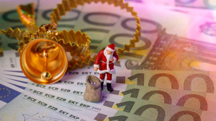 Symbolbild: Ein Weihnachstmann mit Gabensack steht auf mehreren Geldscheinen (Quelle: imago/Christoph Hardt)