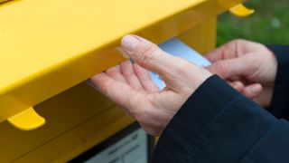 Symbolbild: Eine Person wirft einen Brief in einen Postbriefkasten. (Quelle: imago images/Frank Röder)
