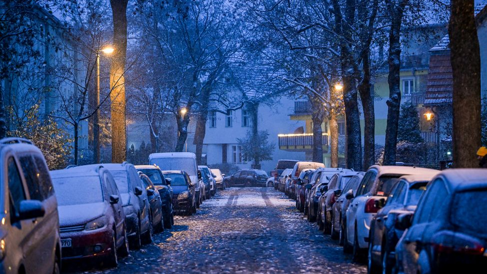 Mit Schnee bedeckt ist am Nachmittag eine Kopfsteinpflasterstraße und die dort parkenden Autos in Karlshorst. (Quelle: dpa/J. Kalaene)