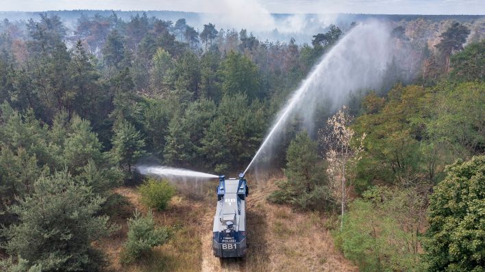 Ein Wasserwerfer der Brandenburger Polizei löscht am 27.07.2022 einen Waldbrand im Landkreis Elbe-Elster. (Quelle: dpa/Jan Woitas)