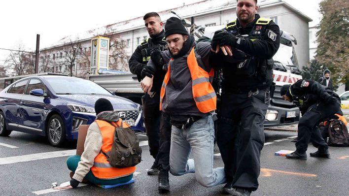 Polizisten tragen einen Teilnehmer einer Sitzblockade auf der Prenzlauer Allee von der Strasse. (Quelle: dpa/Carsten Koall)