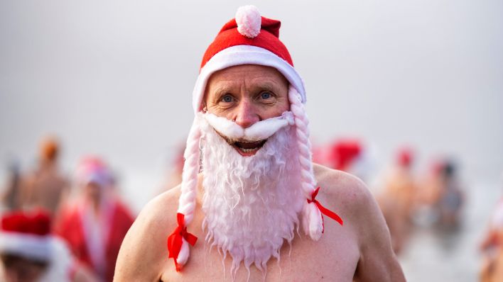 Ein Mitglied des Vereins „Berliner Seehunde“ trägt beim Weihnachtsbaden im Orankesee ein Weihnachtskostüm.(Quelle:dpa/C.Gateau)