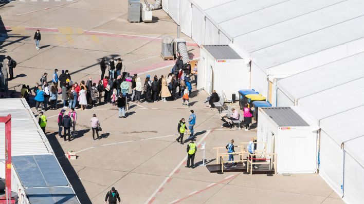 Archivbild:Menschen stehen am 28.03.2022 im Berliner Ankunftszentrum für Flüchtlinge aus der Ukraine am ehemaligen Flughafen Tegel vor einem Zelt Schlange.(Quelle:dpa/C.Soeder)