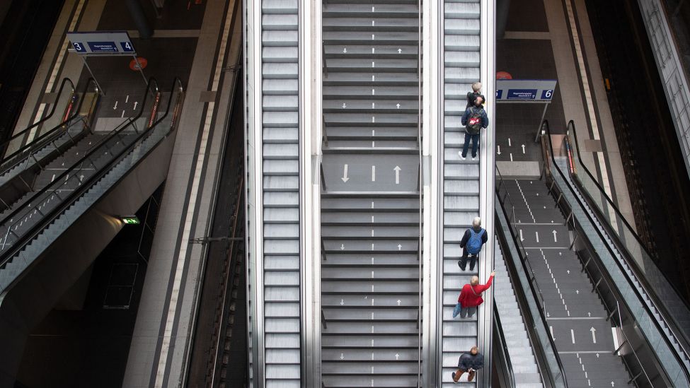 Reisende stehen auf einer Rolltreppe im Hauptbahnhof in Berlin. (Quelle: dpa/Paul Zinken)