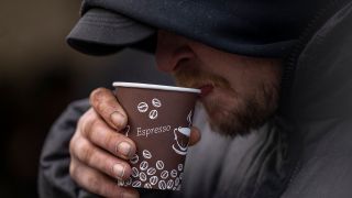 Ein obdachloser Mann trinkt warmen Tee vor einem Versorgungszelt in der Kleiderkammer der Berliner Stadtmission. (Quelle: dpa/Monika Skolimowska)