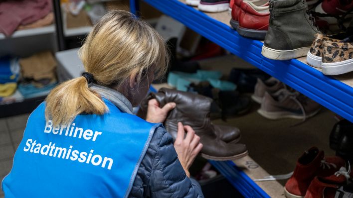 Eine Mitarbeiterin der Berliner Stadtmission sortiert in der Kleiderkammer gespendete Schuhe und räumt sie in Regale ein. (Quelle: dpa/Monika Skolimowska)
