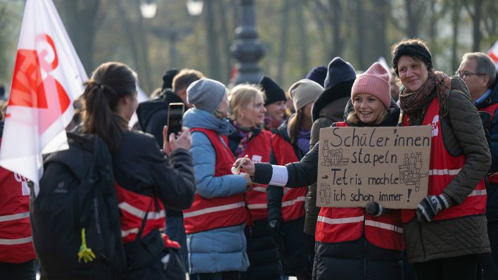 Archivbild: Zwei Teilnehmerinnen der Demonstration der Gewerkschaft Erziehung und Wissenschaft (GEW) fotografieren sich bei der Kundgebung vor dem Brandenburger Tor mit einem Schild. (Quelle: dpa/M. Skolimowska)