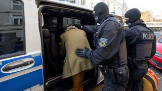 Bei einer Razzia gegen sogenannte «Reichsbürger» führen vermummte Polizisten, nach der Durchsuchung eines Hauses Heinrich XIII Prinz Reuß zu einem Polizeifahrzeug. (Quelle: dpa/Boris Roessler)