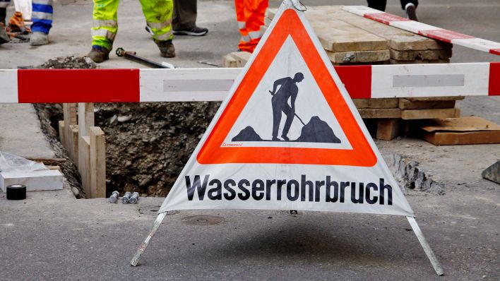 Symbobild: Schild mit Aufschrift "Wasserrohrbruch" vor einer Absperrung.(Quelle:imago images/Geisser)