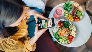 Eine Frau nimmt am 23.04.2021 mit ihrem Smartphone Essen auf. (Quelle: imago images/Jordi Bataller)