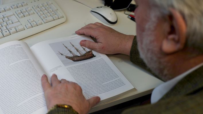 Professor Ulrich van der Heyden blättert im Buch "Rote Adler an Afrikas Küste", in dem er die Geschichte von Groß Friedrichsburg festgehalten hat (Quelle: rbb/Oliver Noffke)