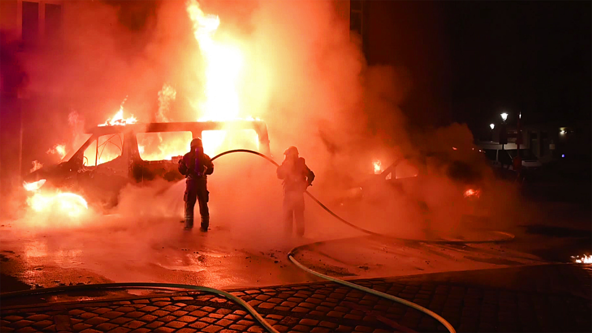 Einsatzkräfte der Feuerwehr versuchen das brennende Polizeiauto zu löschen.(Quelle:TV Newskontor)