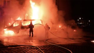 Einsatzkräfte der Feuerwehr versuchen das brennende Polizeiauto zu löschen.(Quelle:TV Newskontor)