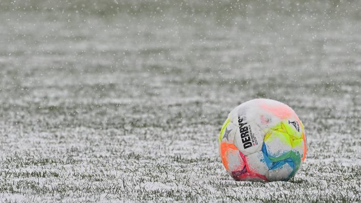 Ein Fußball auf verschneitem Rasen (Bild: IMAGO/Zink)