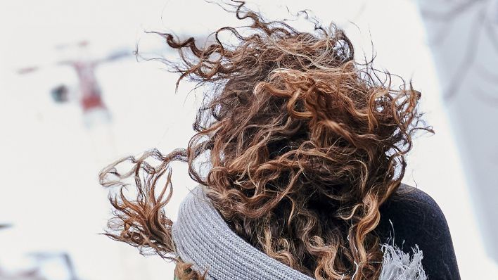 Archivbild: Eine Frau geht am 17.02.2022 mit wehendem Haar und fliegendem Schal Richtung Berliner Alexanderplatz. (Quelle: dpa/Annette Riedl)