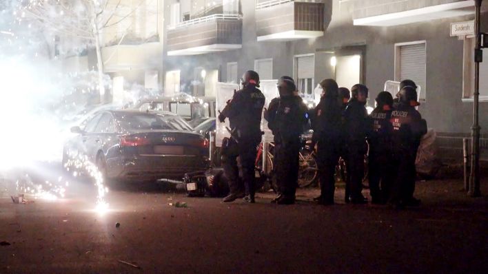 Polizeibeamte stehen am 31.12.2022 hinter explodierendem Feuerwerk in Berlin. (Quelle: dpa/TNN/Julius-Christian Schreiner)