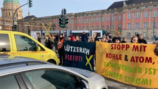Aus Protest gegen die Räumung des rheinischen Dorfes Lützerath für den Braunkohletagebau haben rund 50 Klimaaktivisten in Potsdam kurzzeitig den Verkehr auf der Breiten Straße in beiden Fahrtrichtungen blockiert. (Quelle: dpa/Klaus Peters)