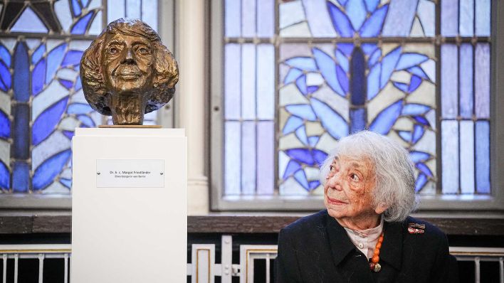 Margot Friedländer, Holocaust-Überlebende, sitzt nach der Verleihung des Bundesverdienstkreuzes 1. Klasse neben einer Büste, die sie zeigt. Die Büste hat die Künstlerin Stephanie von Dallwitz gefertigt. (Foto: Kay Nietfeld/dpa)