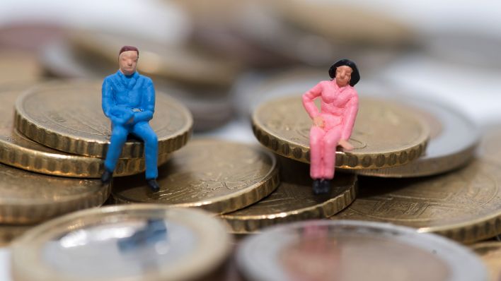 Symbolbild: Die Figuren eines Mannes und einer Frau sitzen auf Geldmünzen (Quelle: dpa/Andrea Warnecke)