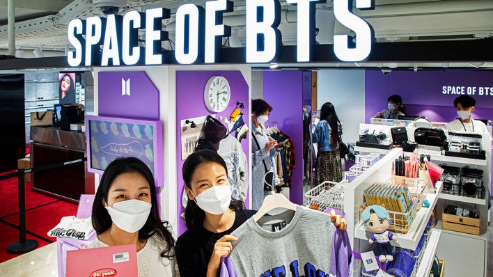 Archivbild:Mitarbeitende zeigen am 09.06.2022 Merchandise-Artikel in einem BTS Store in Seoul.(Quelle:dpa/Yonhap)