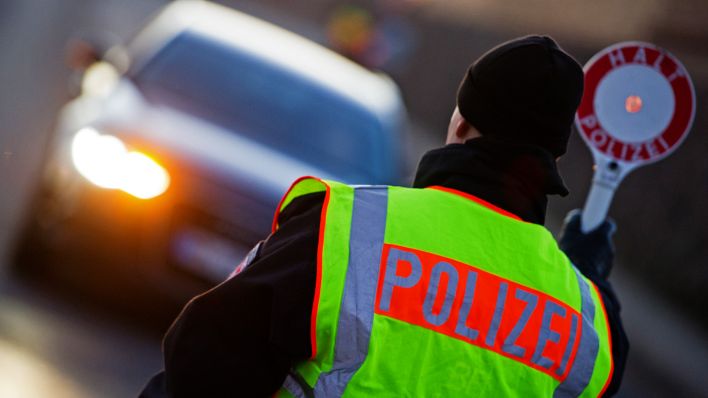 Symbolbild:Ein Polizist in Brandenburg stoppt ein Auto.(Quelle:dpa/P.Pleul)