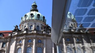 Das Rathaus spiegelt sich in der Scheibe einer Straßenbahnhaltestelle. (Quelle: dpa/Soeren Stache)