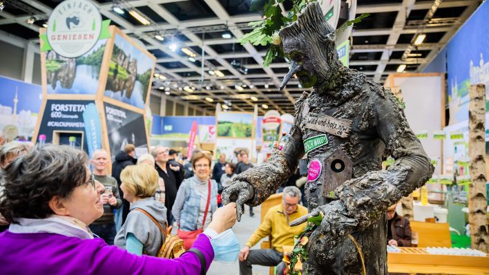Eine Frau begrüßt am letzten Tag der Internationalen Grünen Woche am Stand des «Landesbetriebs Wald und Holz Nordrhein-Westfalen» einen "Baummenschen". (Quelle: dpa/C. Soeder)