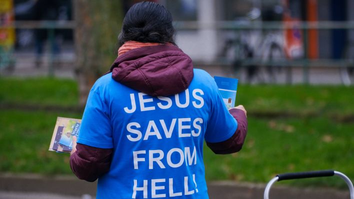 Eine Anhängerin einer christlich-evangelikalen Glaubensgemeinschaft missioniert mit Broschüren auf der Straße. (Quelle: imago images)