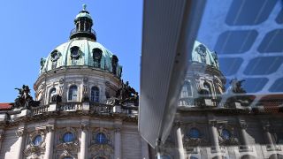Symbolbild: Das Rathaus spiegelt sich in der Scheibe einer Straßenbahnhaltestelle. (Quelle: dpa/S. Stache)