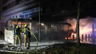 Einsatzkräfte der Feuerwehr löschen in der Silvesternacht an der Sonnenallee im Bezirk Neukölln einen brennenden Bus, der von Unbekannten angezündet worden war. (Quelle: dpa/Paul Zinken)