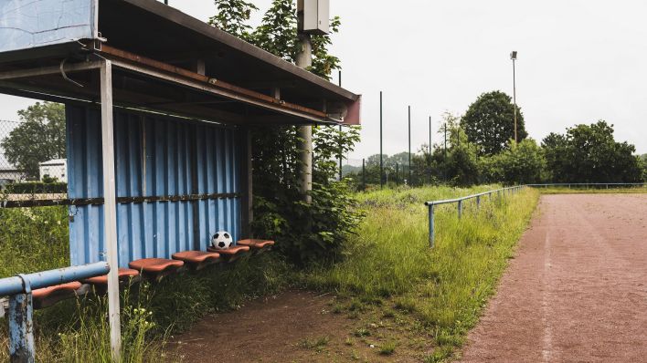 Eine verlassene Auswechselbank an einem verwachsenem Fußballplatz (imago images/Westend61)
