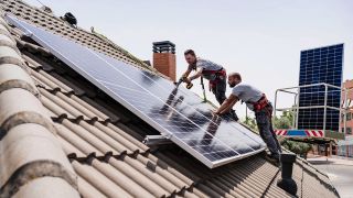 Symbolbild: Zwei Arbeiter installieren eine Solarzelle auf dem Dach (Quelle: IMAGO/Eva Blanco)