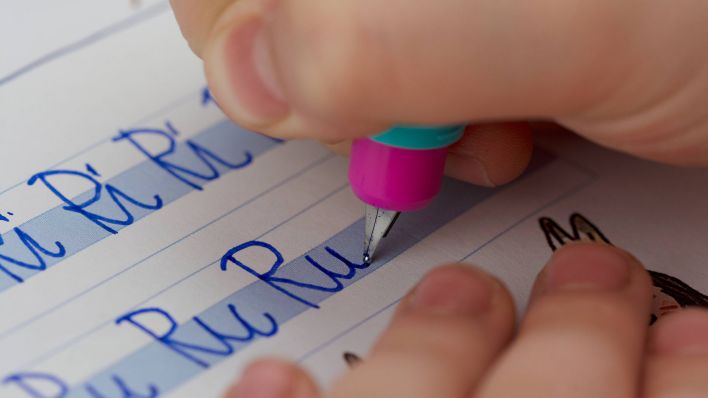 Ein Grundschulkind schreibt in ein Schreibheft. (Quelle: imago-images/Illupics)