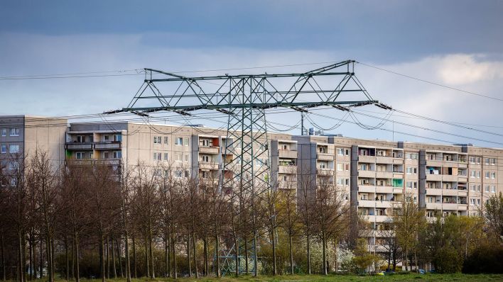Ein Strommast steht vor einem Plattenbau in Berlin. (Quelle: imago-images/David Weyand)