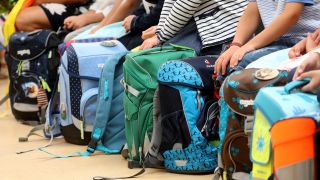 Symbolbild: Schulranzen von Kindern einer Grundschule in Rostock stehen am 18.08.2018 bei der Einschulung vor den Schülern. (Quelle: dpa-Bildfunk/Bernd Wüstneck)