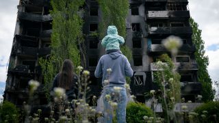 Symbolbild: Eine Familie blickt auf ein zerstörtes Gebäude. (Quelle: dpa/Dominic Chiu)