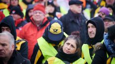 Ein Demonstrant trägt am 06.02.2023 eine Capy mit dem Post-Logo, während er zusammen mit anderen Angestellten der Deutschen Post vor der Ver.di Bundeszentrale auf der Schillingbrücke streikt. (Quelle: dpa/Annette Riedl)