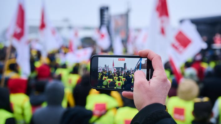Die Demonstrantin filmt am 06.02.2023 den Warnstreik vor der Ver.di Bundeszentrale auf der Schillingbrücke. (Quelle: Picture Alliance/Annette Riedl)