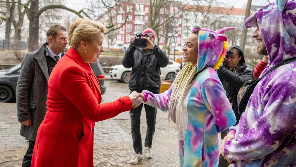 Franziska Giffey (SPD), Regierende Bürgermeisterin von Berlin und Spitzenkandidatin der Berliner SPD, begrüßt am 12.02.2023 vor ihrem Wahllokal in Berlin-Friedrichshain zwei Wähler in Einhorn-Kostümen. (Quelle: dpa/Christophe Gateau)