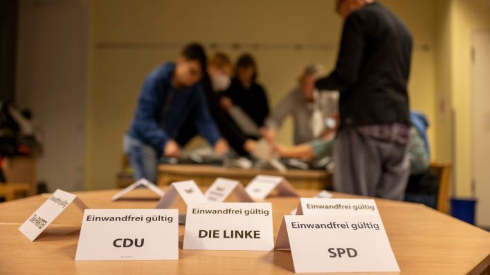 Symbolbild: Zettel mit den Parteinamen und der Aufschrift „Einwandfrei gültig“ stehen nach der wiederholten Wahl auf einem Tisch in einem Wahllokal (Quelle: dpa/Monika Skolimowska)