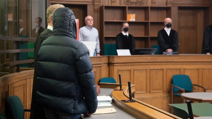 Ein 24 Jahre alter Mann hält sich am 24.02.2023 im Gerichtssaal eine Mappe vor das Gesicht. (Quelle: dpa/Paul Zinken)