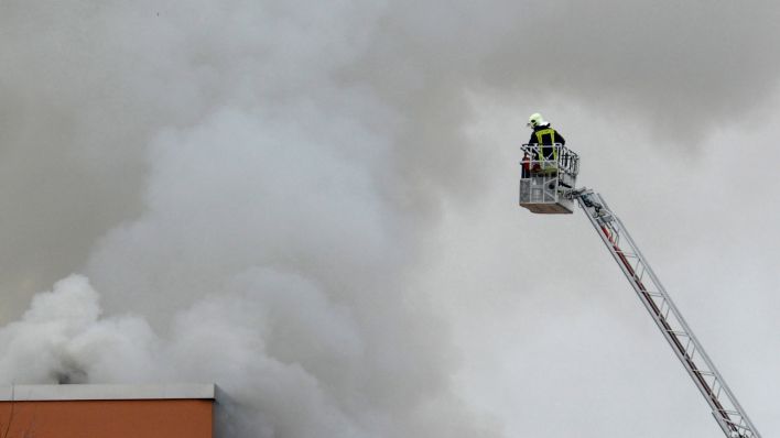 Symbolbild: Ein Feuerwehrmann steht am 11.01.2016 während eines Brandes in einem Mehrfamilienhaus in Elsterwerda (Brandenburg) auf einer Drehleiter. (Quelle: dpa-Zentralbild/Veit Rösler)