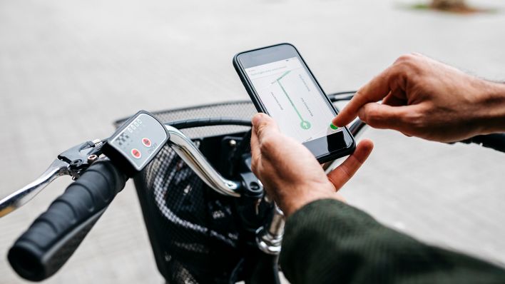 Symbolbild:Ein Radfahrer gibt etwas in seine Navigations-App auf seinem Smartphone ein.(Quelle:dpa/J.Rovirosa)
