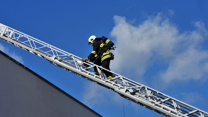 Symbolbild:Ein Feuerwehrmann klettert eine Leiter hinauf.(Quelle:dpa/M.Schutt)