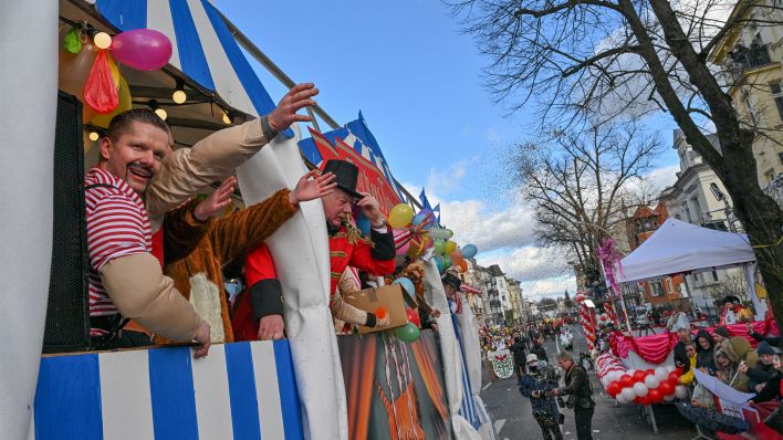 Teilnehmer am 30. Karnevalsumzug «Zug der fröhlichen Leute» feiern auf einem Wagen (Bild: dpa/Patrick Pleul)